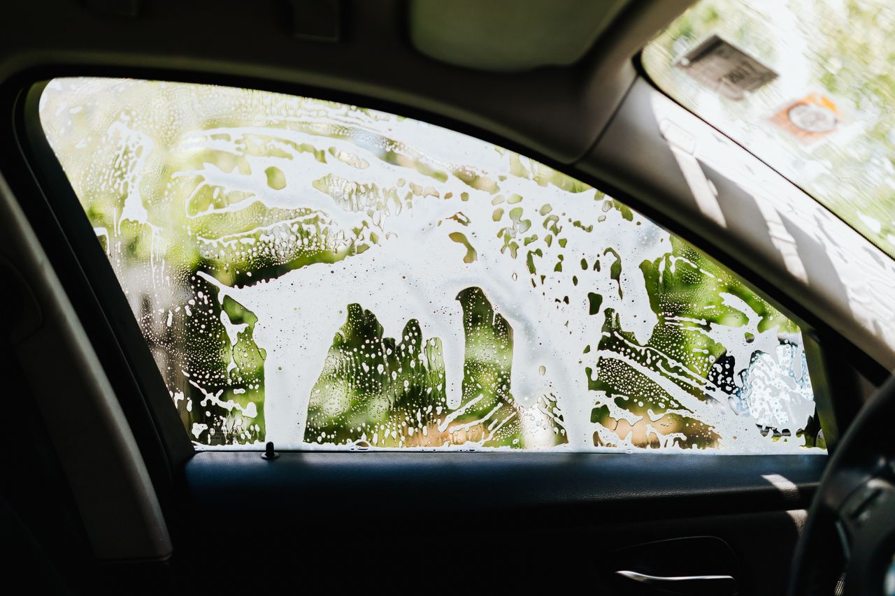 services-01 Seen from inside a car, the window is covered with soapy water during a car wash.
