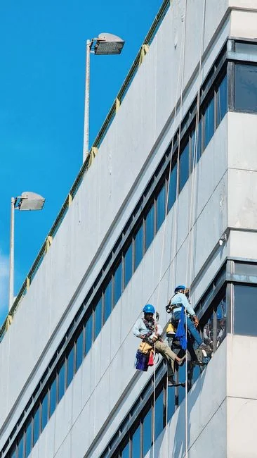 heros-img Construction workers hang from the side of a newly constructed building.